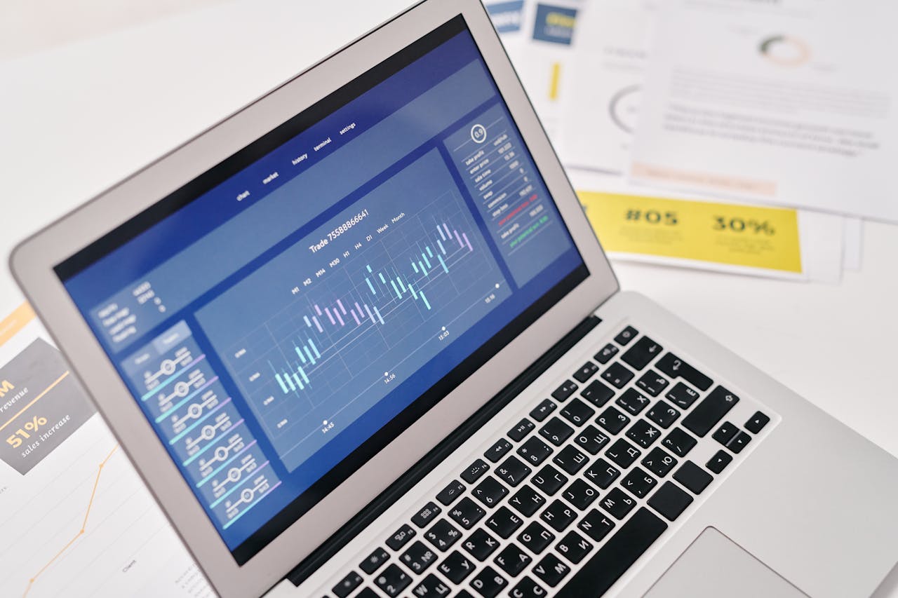 about-01 Open laptop displaying financial graphs and analytics with documents nearby, ideal for business presentations.